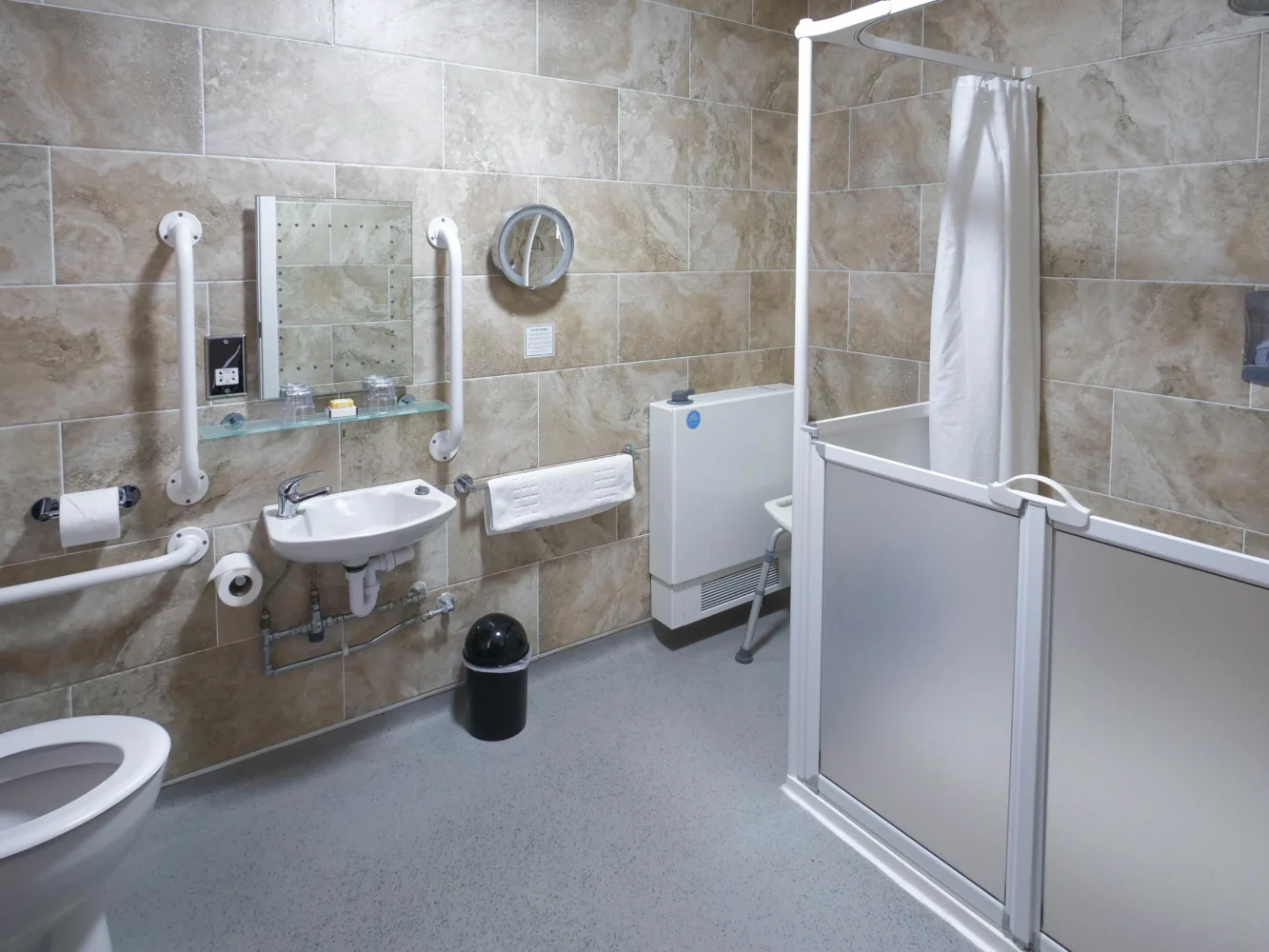 Modern tiled hotel bathroom with shower, sink, and toilet