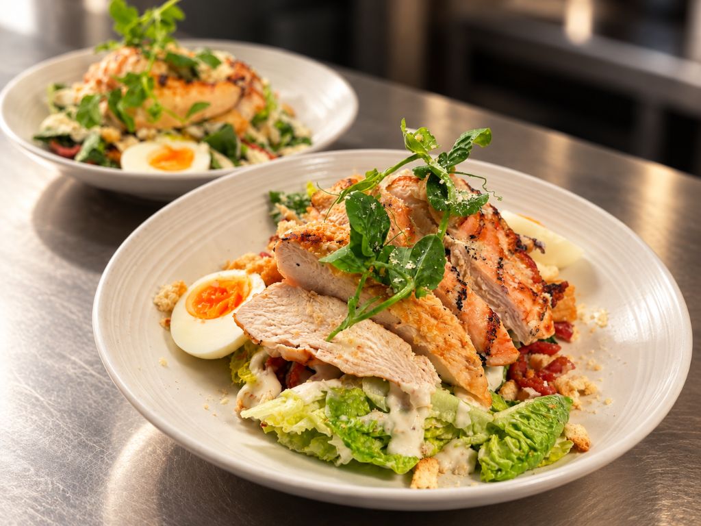 Chicken salad with sliced chicken, soft-boiled egg, little gem lettuce, croutons and pea shoots